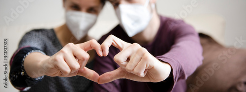 couple with face mask doing a heart with their hands