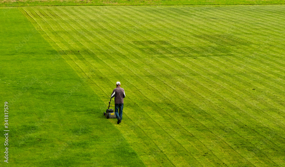 lawn mower cuts grass on the football field while working. lawn mower cuts grass on the football field while working.