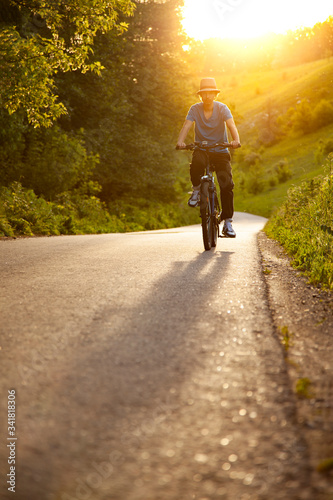 Teenager riding a bike on the road summer sunlit, bicycle ride outdoors
