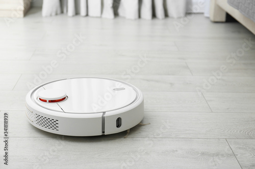 Hoovering floor with modern robotic vacuum cleaner indoors. Space for text