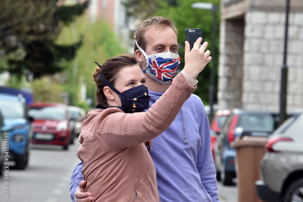 Young couple, man and woman, wearing DIY facemasks, taking a selfie with mobile phone. Young couple, man and woman, wearing DIY facemasks, taking a selfie with mobile phone.
