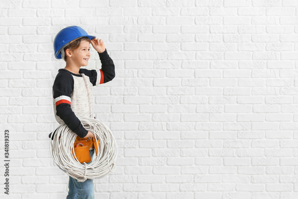 Cute little electrician on white brick background