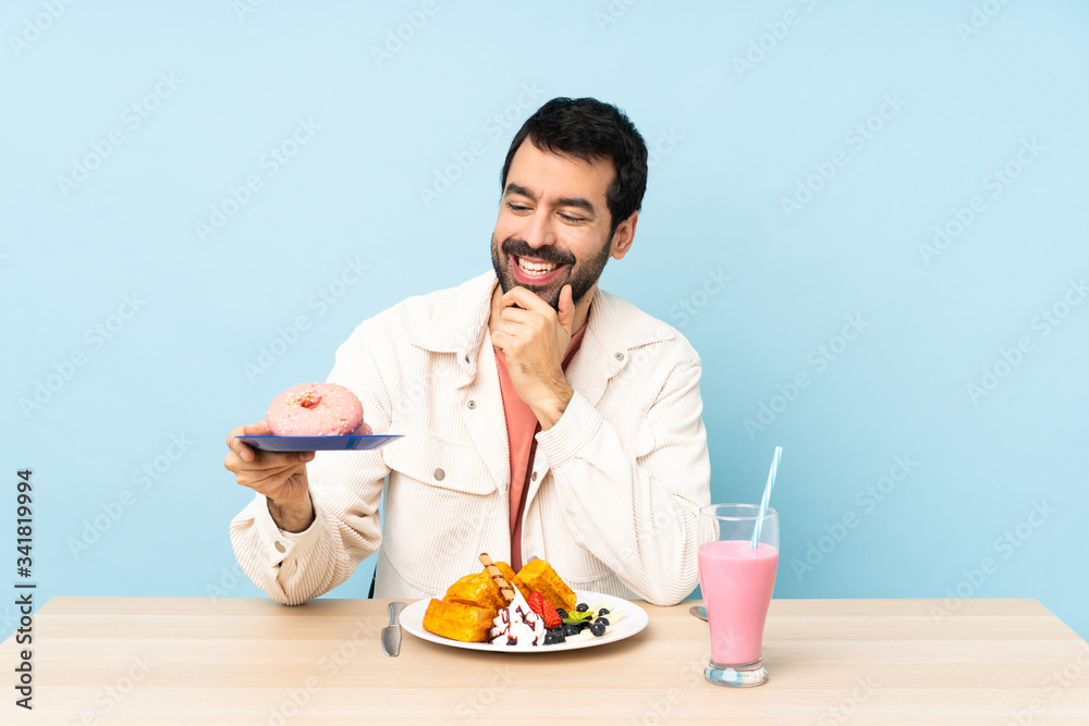 Man at a table having breakfast waffles and a milkshake Man at a table having breakfast waffles and a milkshake