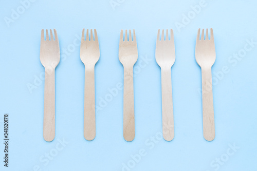 eco friendly disposable kitchenware utensils on blue background. wooden forks and spoons. ecology, zero waste concept. top view. flat lay.