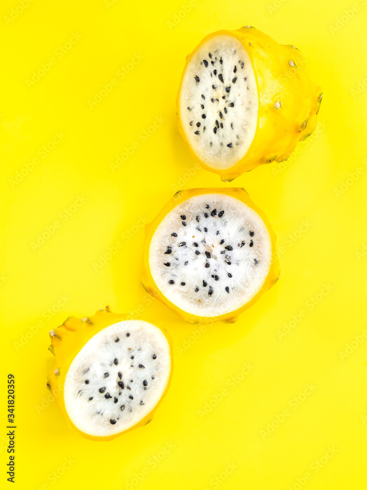 Fototapeta premium Golden dragon fruit on bright yellow background. Exotic tropical fruits top view.