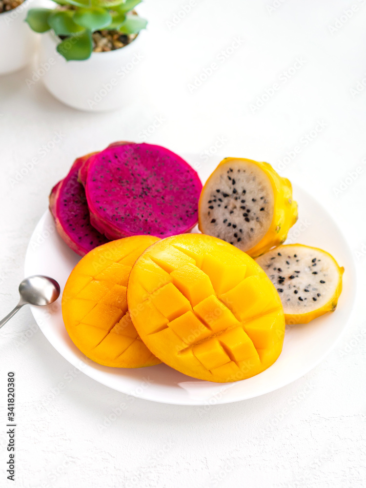 Fresh sweet mango and sliced dragon fruit on white background. Exotic tropical fruits for healthy and vegeterian diet. Copy space.