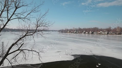 Flying over snow covered houses along frozen icy lakefront, Michigan USA
