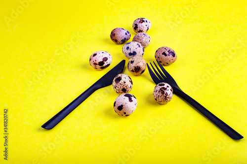 Beautiful yellow background with quail eggs. Food background with knife and fork. Quail eggs.