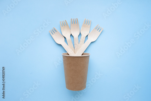 eco friendly disposable kitchenware utensils on blue background. wooden forks and spoons in paper cup. ecology  zero waste concept. top view. flat lay.