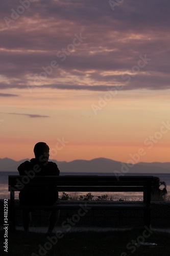 silhouette of a man sitting on a bench at sunset
