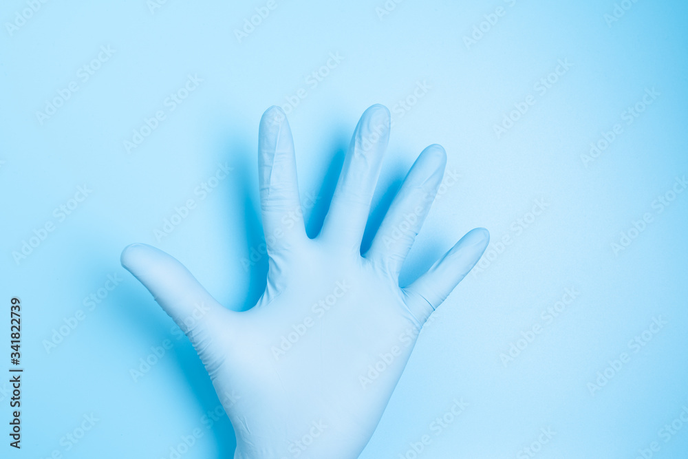 Male palm in medical latex hand glove isolated on blue background, high five sign Male palm in medical latex hand glove isolated on blue background, high five sign