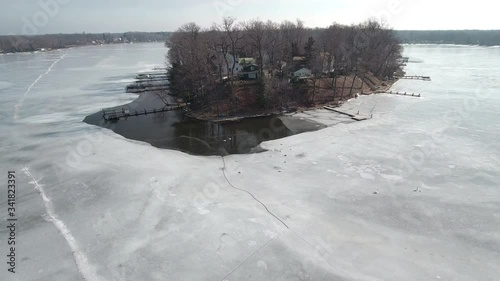 Flying over snow covered houses along frozen icy lakefront, Michigan USA