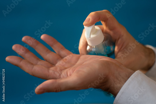 Sanitizer gel. Hand antiseptic. blue bottle of antibacterial product in man s hands on a blue background.epidemic of coronavirus. Hygiene and health concept.