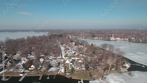 Flying over snow covered houses along frozen icy lakefront, Michigan USA