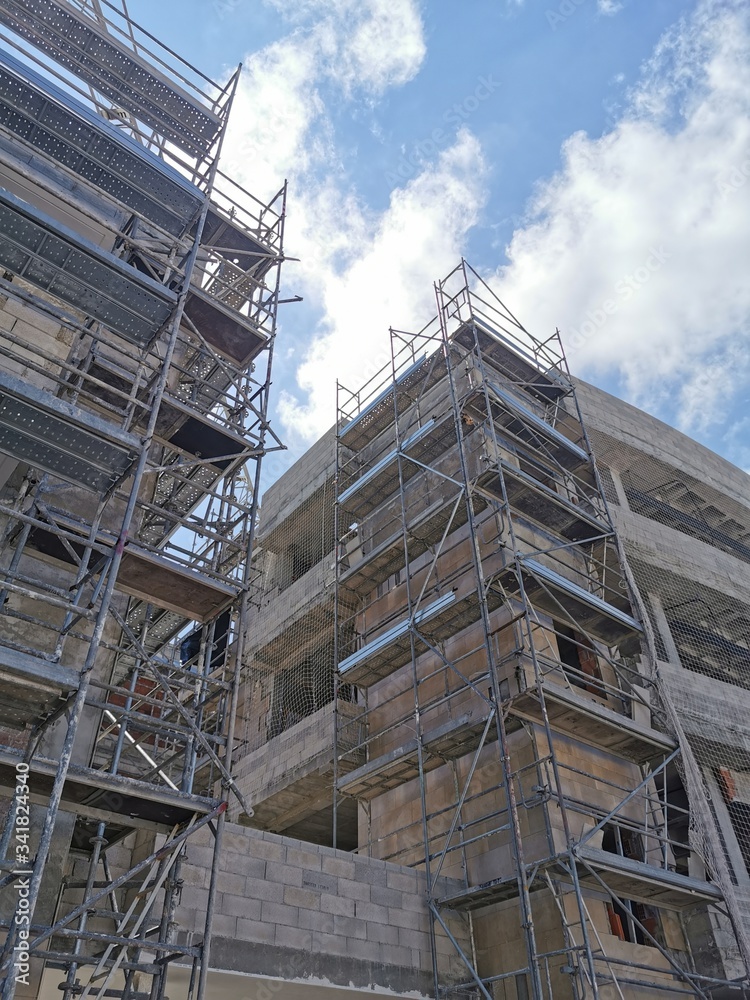 building under construction in scaffolding and concrete floors against a blue sky