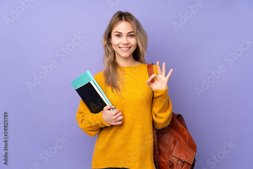 Teenager Russian student girl isolated on purple background showing an ok sign with fingers