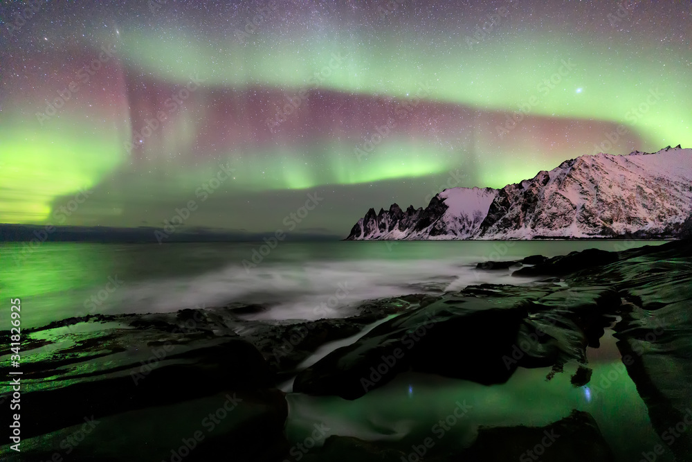 Naklejka premium Aurora borealis over the Ersfjord Beach. Senja island at night, Europe Senja island in the Troms region of northern Norway. Long exposure shot.