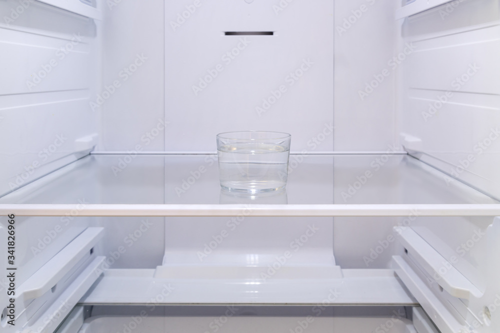 a glass of water on the shelf in the empty refrigerator a glass of water on the shelf in the empty refrigerator