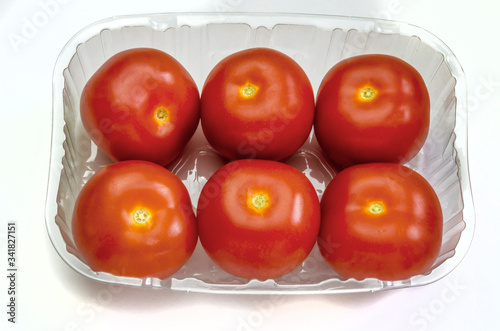 Six tomatoes in a plastic container. Fresh from supermarket and ready to use for salads and other usage. 