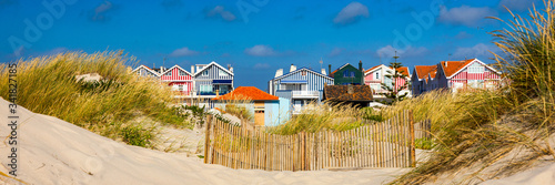 Idyllic and quaint beach houses seen from beach dunes. Beach houses with colorful stripes from Costa Nova, Aveiro, Portugal.