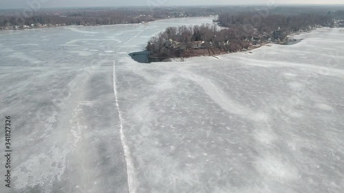 Flying over snow covered houses along frozen icy lakefront, Michigan USA