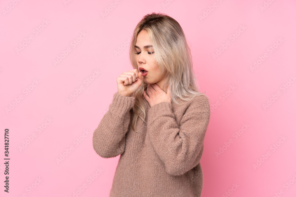 Teenager blonde girl wearing a sweater over isolated pink background is suffering with cough and feeling bad