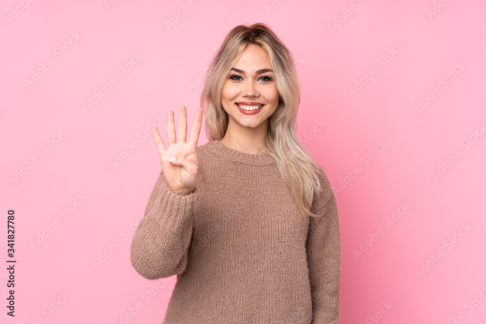 Teenager blonde girl wearing a sweater over isolated pink background happy and counting four with fingers Teenager blonde girl wearing a sweater over isolated pink background happy and counting four with fingers
