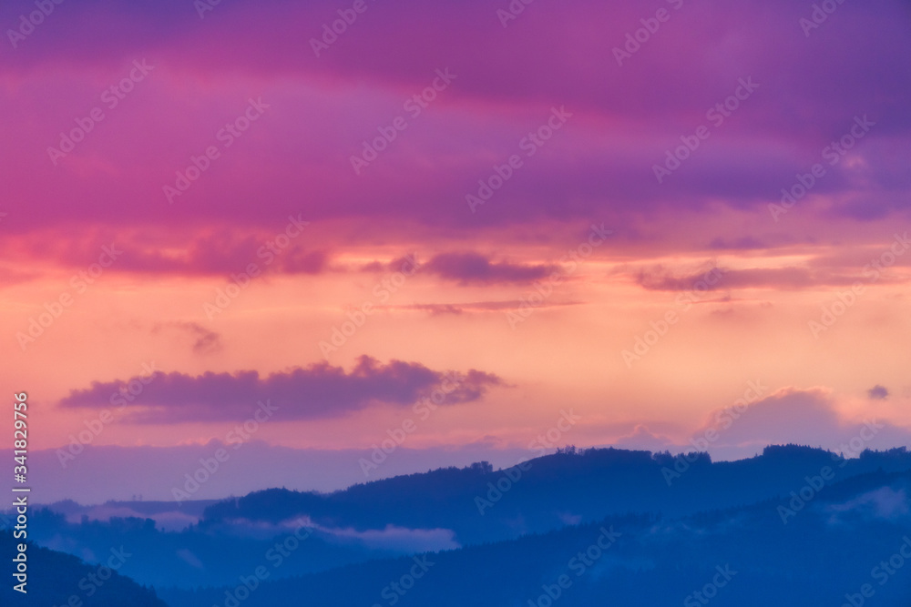 Sky above a mountain landscape at twilight, covered with colorful clouds.
