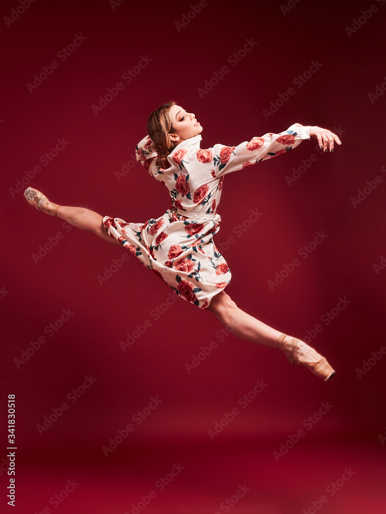 Ballet dancer, ballerina dancing isolated on red background.