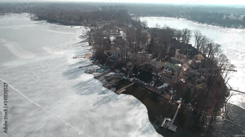Flying over snow covered houses along frozen icy lakefront, Michigan USA