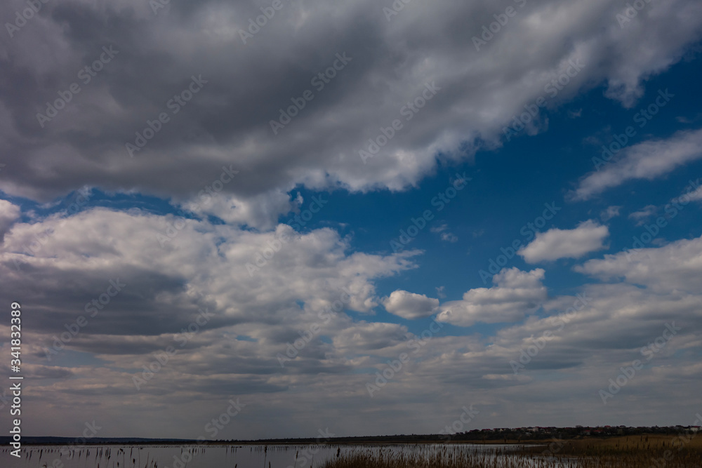 Cloudy dramatic sky with a narrow strip of horizon below. Creative vintage background.