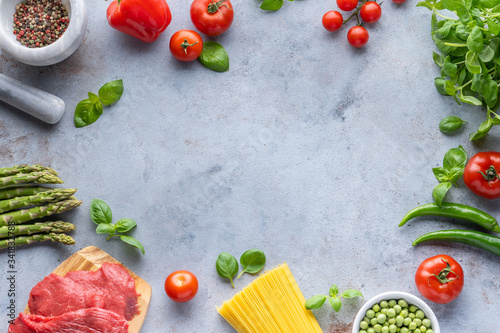 Frame for Italian food. Ingredients for pasta. Cherry tomatoes  meat  spaghetti pasta  garlic  Basil  asparagus  broccoli and spices on a grey grunge background  copy space  top view 
