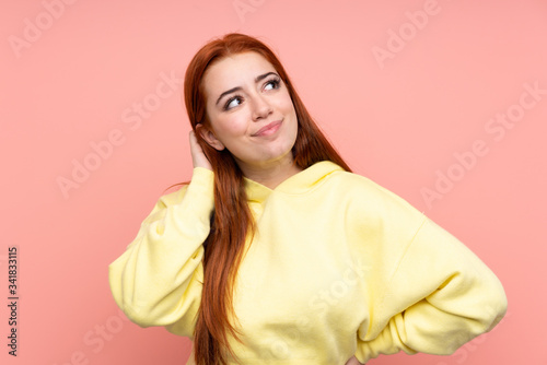 Redhead teenager girl over isolated pink background thinking an idea