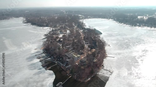Flying over snow covered houses along frozen icy lakefront, Michigan USA