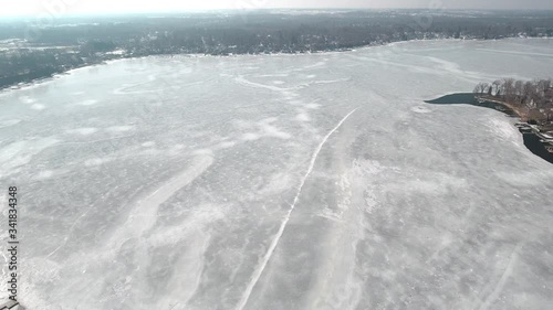 Flying over snow covered houses along frozen icy lakefront, Michigan USA