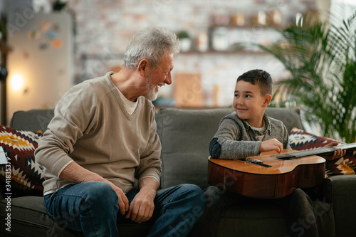 Grandpa and grandson playing guitar. Grandfather and grandson enjoying at home. 
