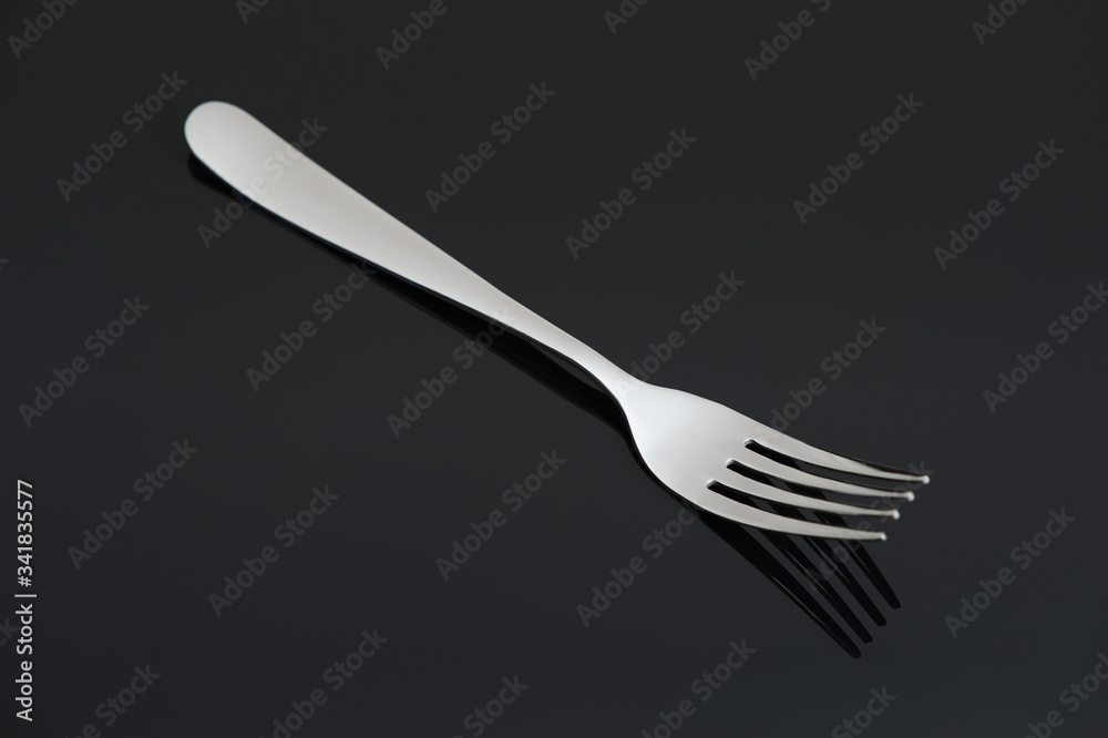 Elegant shiny silver fork on black mirror background. Elegant shiny silver fork on black mirror background.