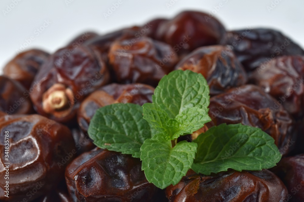 dried date and green mint in a bowl on white wooden table. dried date and green mint in a bowl on white wooden table.
