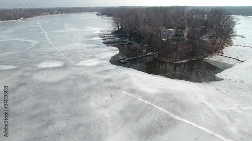 Flying over snow covered houses along frozen icy lakefront, Michigan USA
