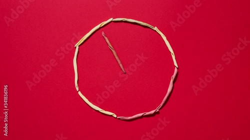 Italian fileja pasta on red background shaped as a clock. 4K stop motion animation seamless loop