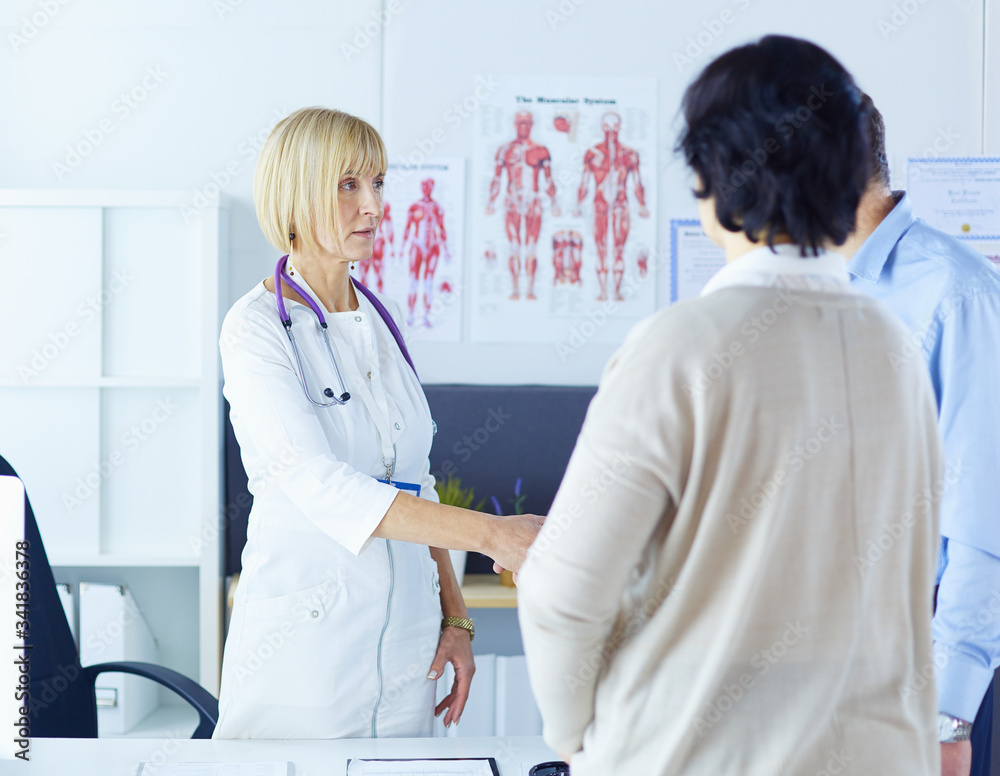Fototapeta premium Female doctor handshaking a patient's hand and smiling