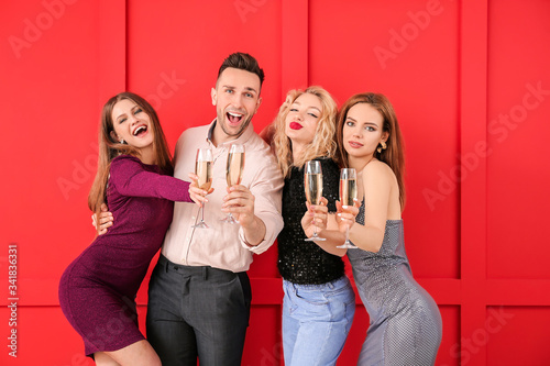 Happy people with glasses of champagne on color background