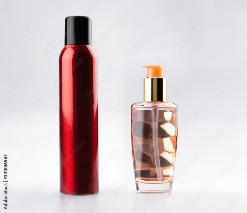 Hair care beauty set. Red aluminum can of hairspray and golden dispenser glass bottle with cosmetic serum elixir oil. Isolated on white background.