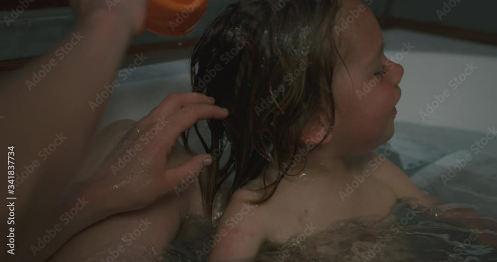 Little boy in bathtub with his mother having a hair wash Little boy in bathtub with his mother having a hair wash