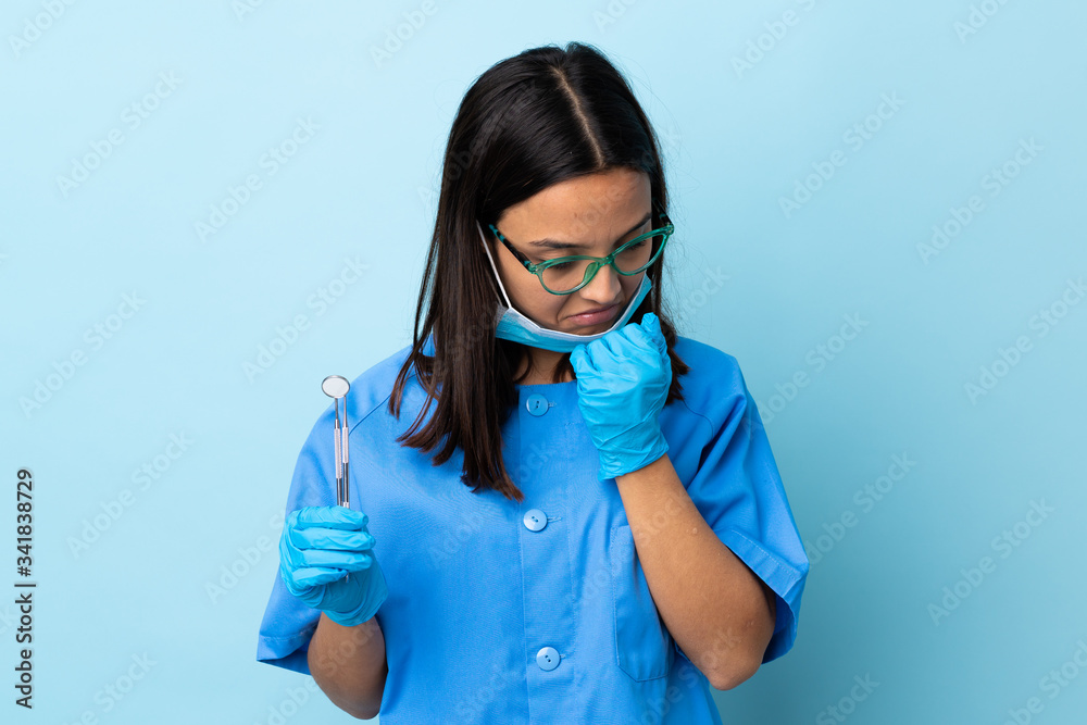 Young brunette mixed race dentist woman holding tools over isolated background having doubts Young brunette mixed race dentist woman holding tools over isolated background having doubts