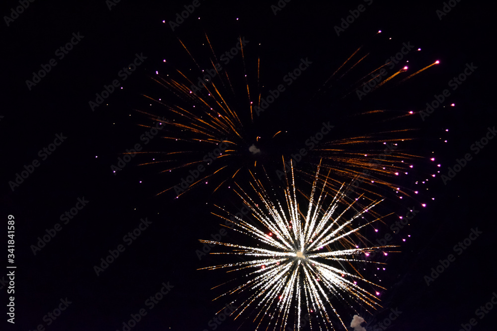 Fototapeta premium Festive salute in night sky. Explosions of fireworks and pyrotechnics in the sky.