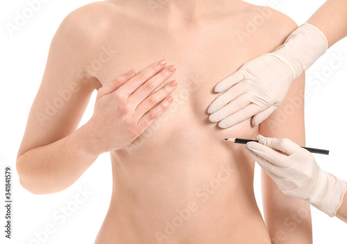 Doctor applying marking on woman s chest against white background. Concept of breast augmentation