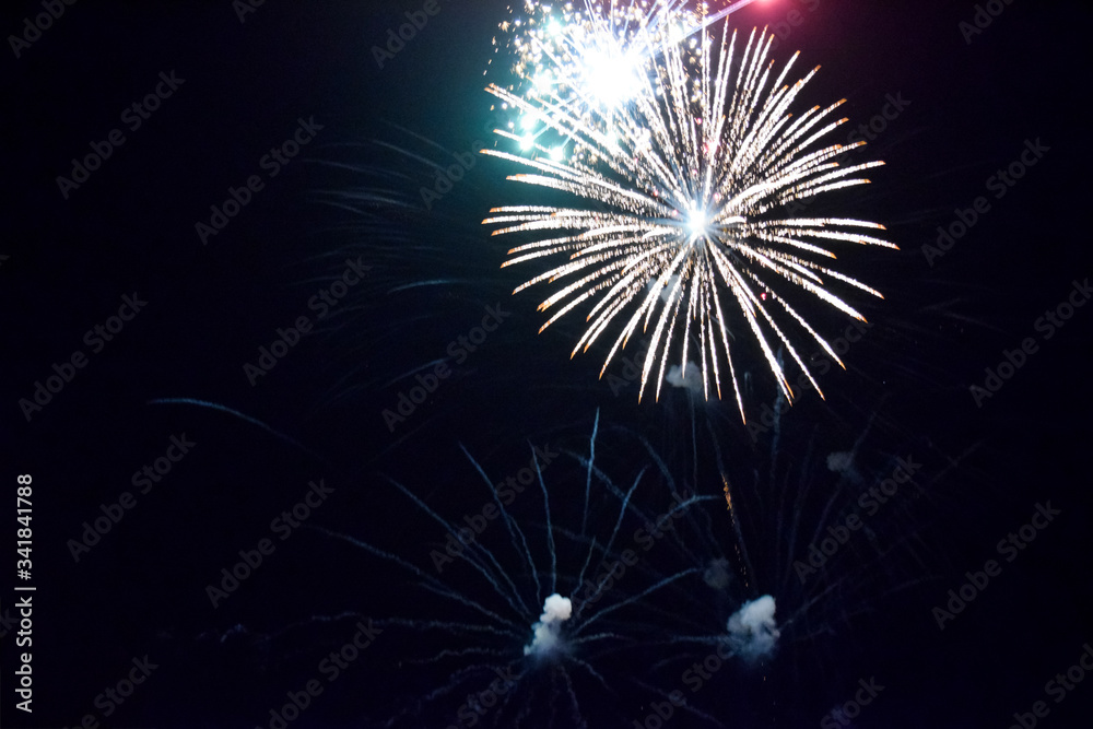 Obraz premium Festive salute in night sky. Explosions of fireworks and pyrotechnics in the sky.
