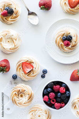Top down view of an arrangement of toasted meringues and berries.