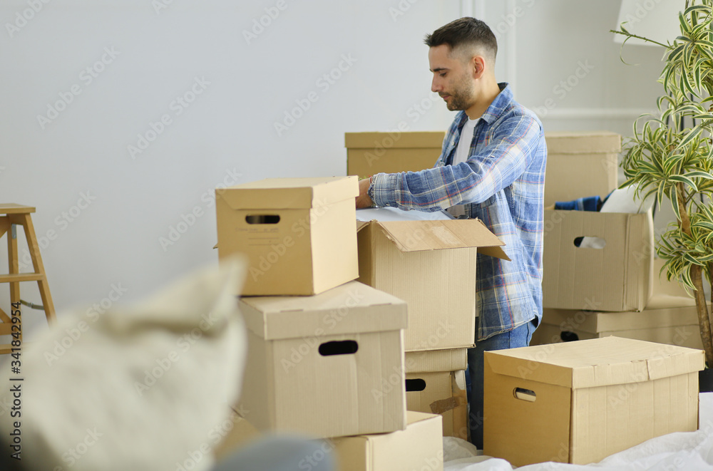 A moving man sitting on the floor in empty apartment, Among the Boxes, Checking the List of Things A moving man sitting on the floor in empty apartment, Among the Boxes, Checking the List of Things